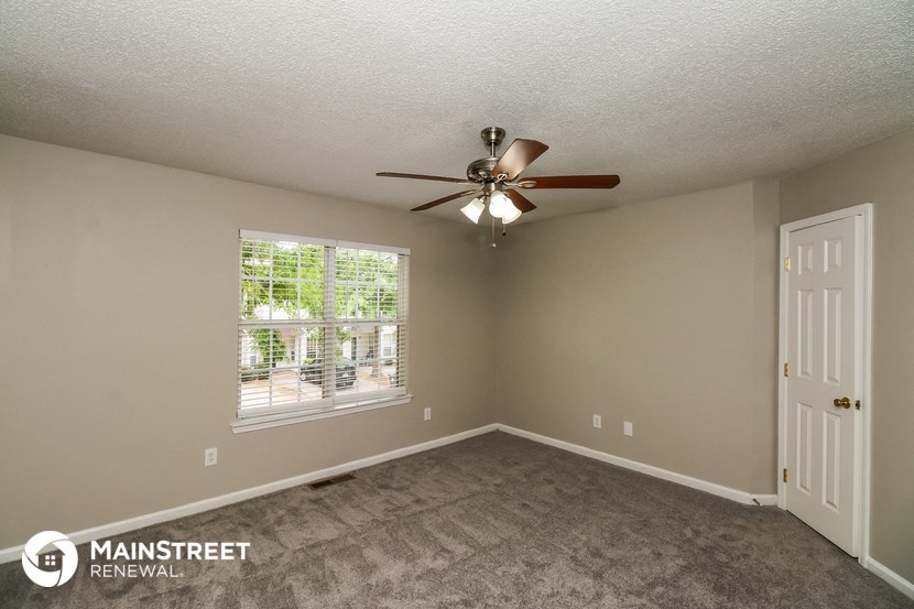 the spacious living room with carpet and ceiling fan