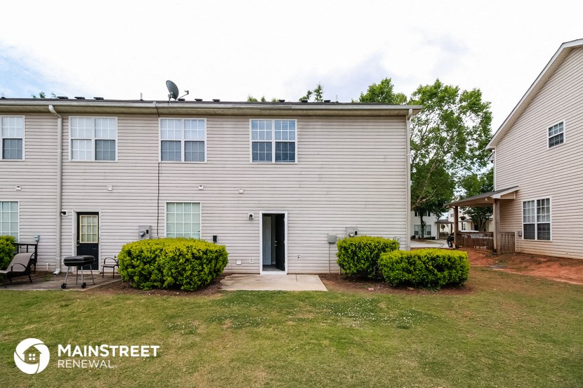 a white house with a lawn and bushes in front of it