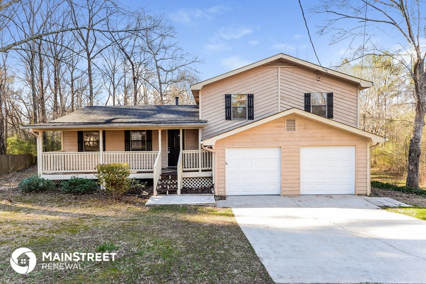 a tan house with a porch and a white garage door