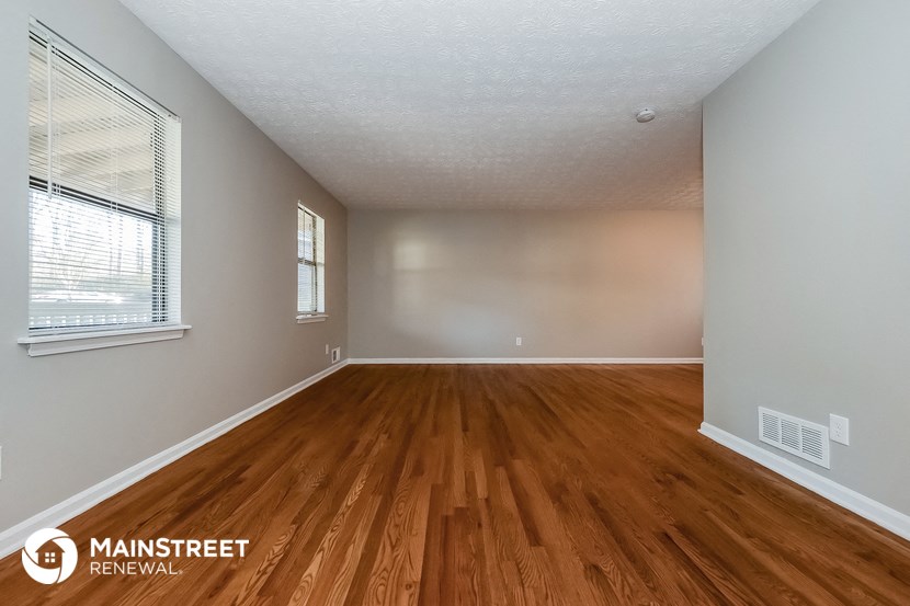 the spacious living room with wood flooring and a large window