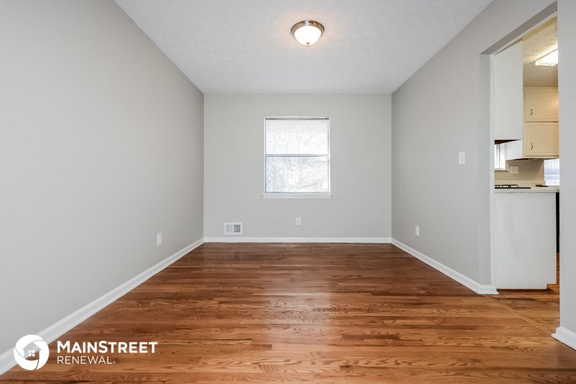 the spacious living room with hardwood flooring and a window