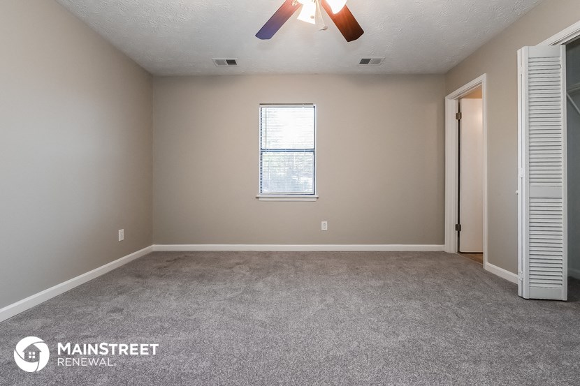 the spacious living room with carpeting and a ceiling fan