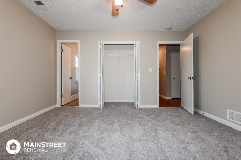 the living room of an apartment with a carpeted floor and two closets
