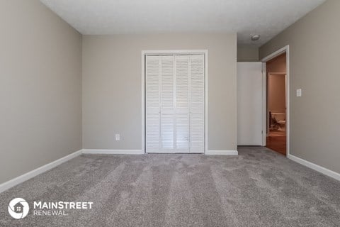 a living room with carpet and an open door to a bedroom