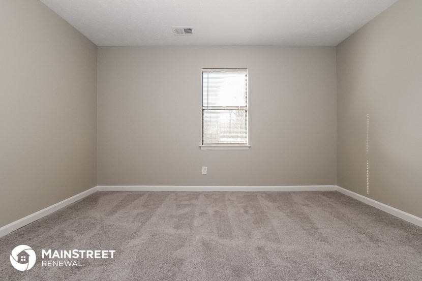 a spacious room with carpeted flooring and a window
