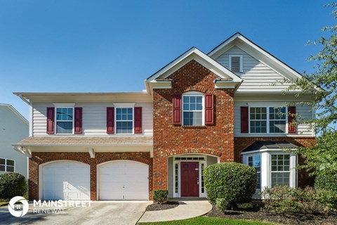 a red brick house with white siding and white garage doors