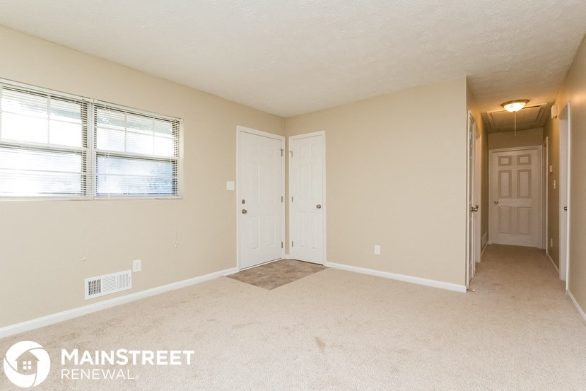 a living room with a door to a hallway and a window