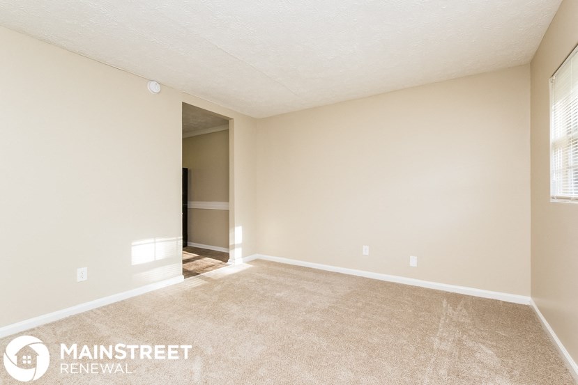 a spacious living room with carpet and a door to a closet