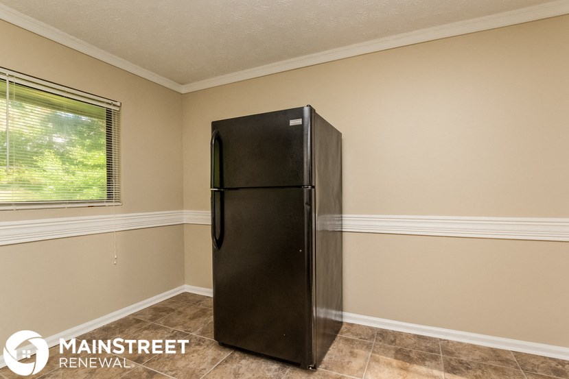 a refrigerator in a beige walled room with a window
