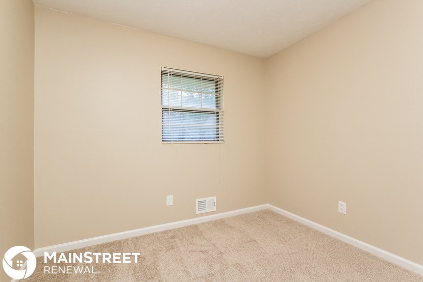 the upstairs bedroom with carpeted flooring and a window