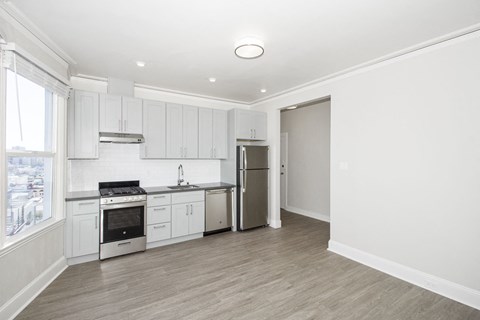 A kitchen with white cabinets and a refrigerator.