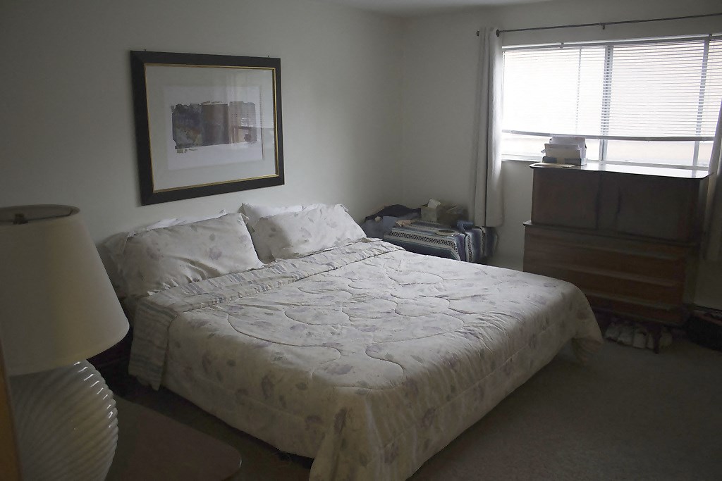 a bedroom with a bed and a dresser and a window