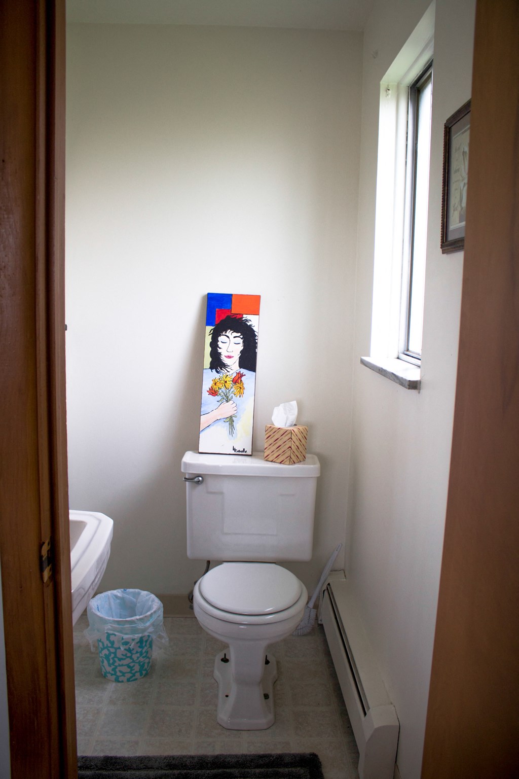 a bathroom with a toilet and a painting on the wall