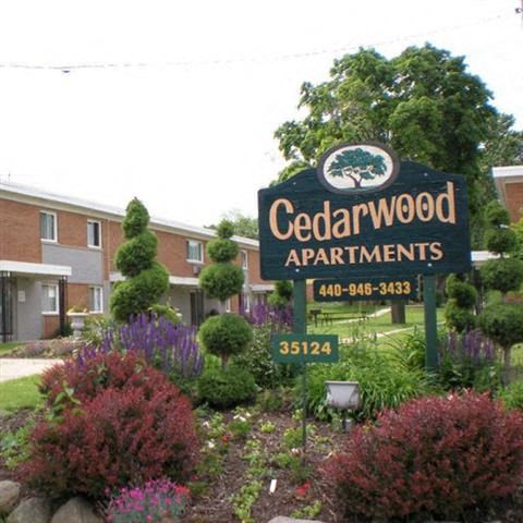 a sign for cedarwood apartments in front of a garden