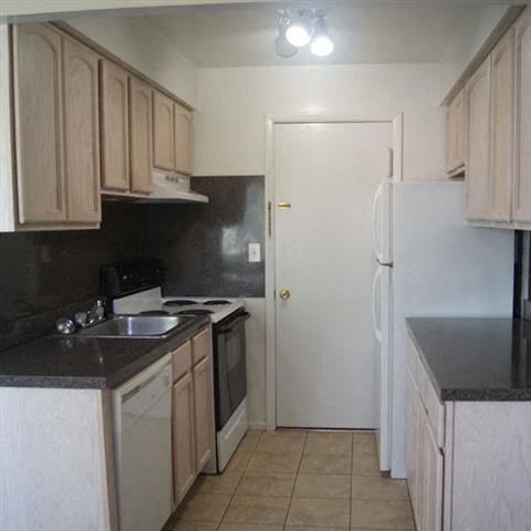 a kitchen with a white refrigerator and a sink