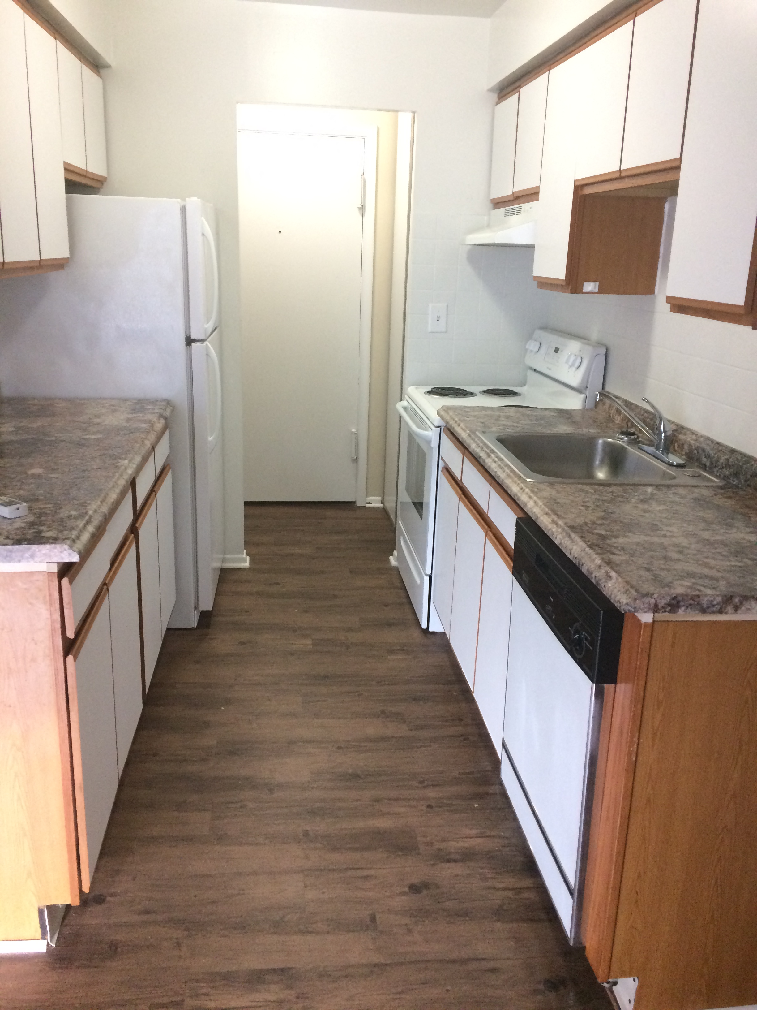 an empty kitchen with wooden floors and white cabinets