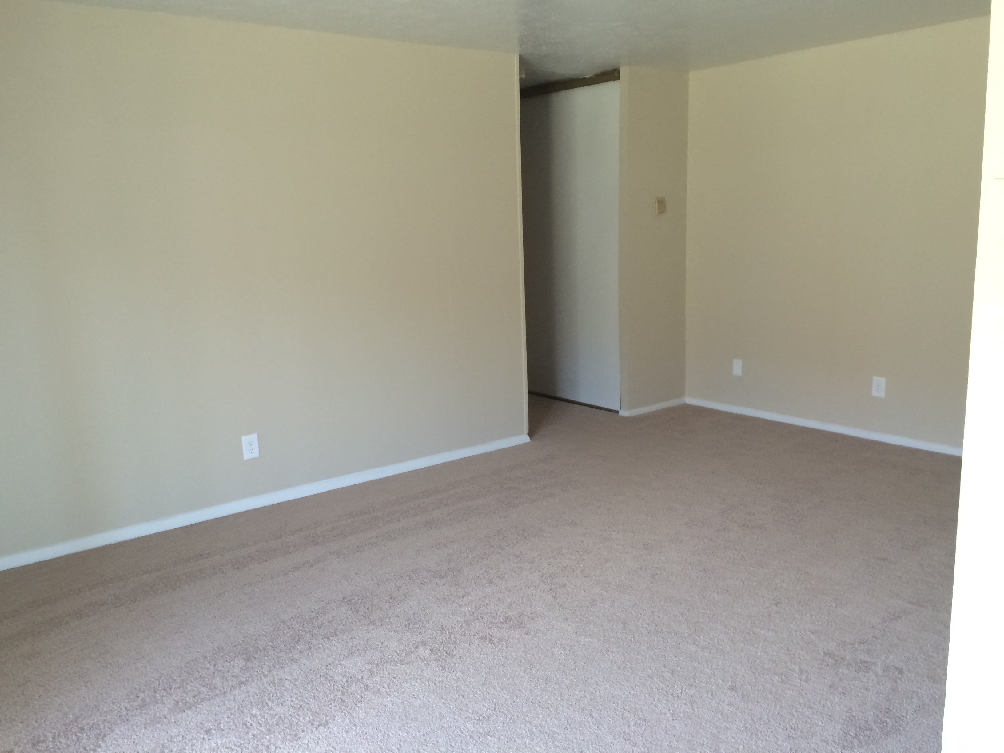 an empty living room with beige carpet and white walls