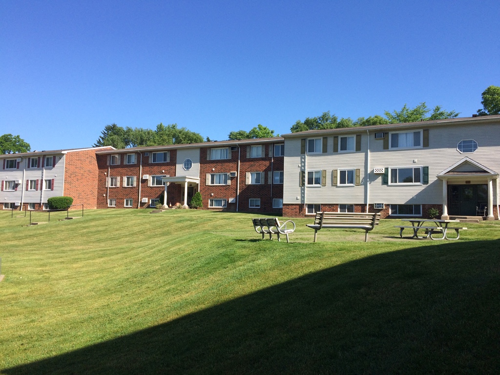 sprawled apartment building with a picnic area in front of it