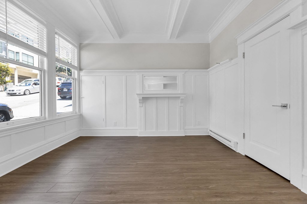 a room with white walls and wood floors and a window