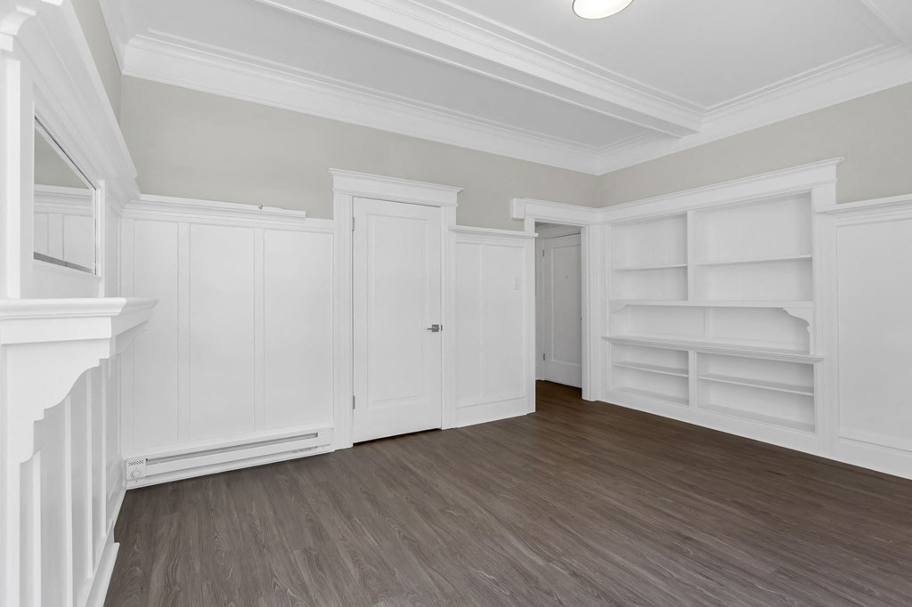 the living room of a house with white walls and wooden floors