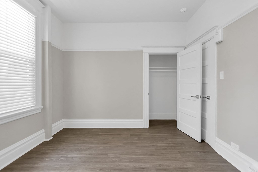 a bedroom with white walls and a door to a closet