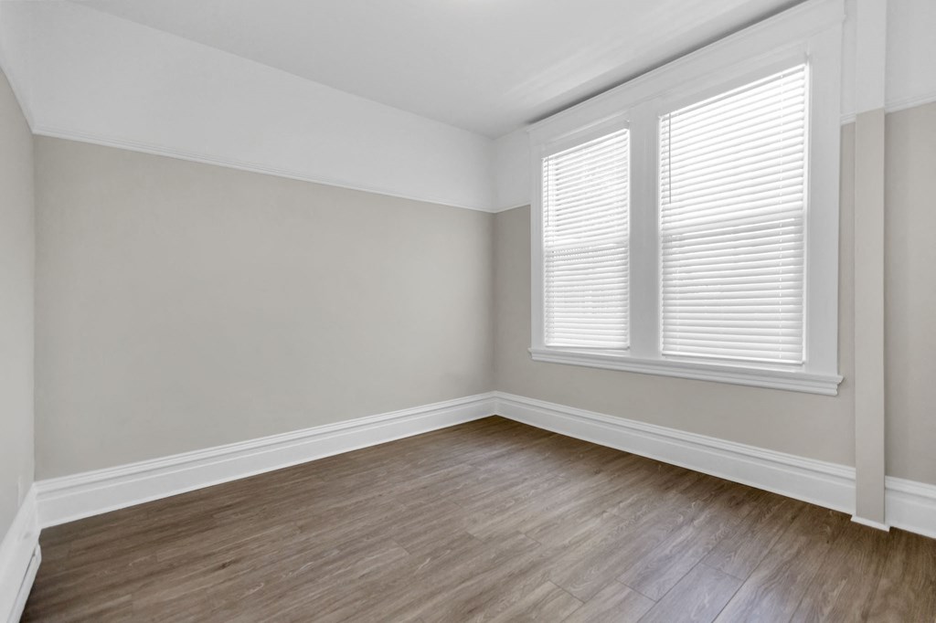an empty room with wood floors and white walls and a window