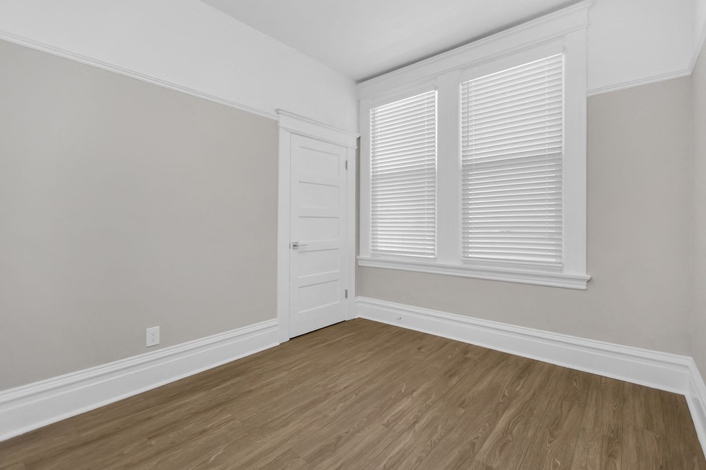a bedroom with white walls and wood floors and a white door