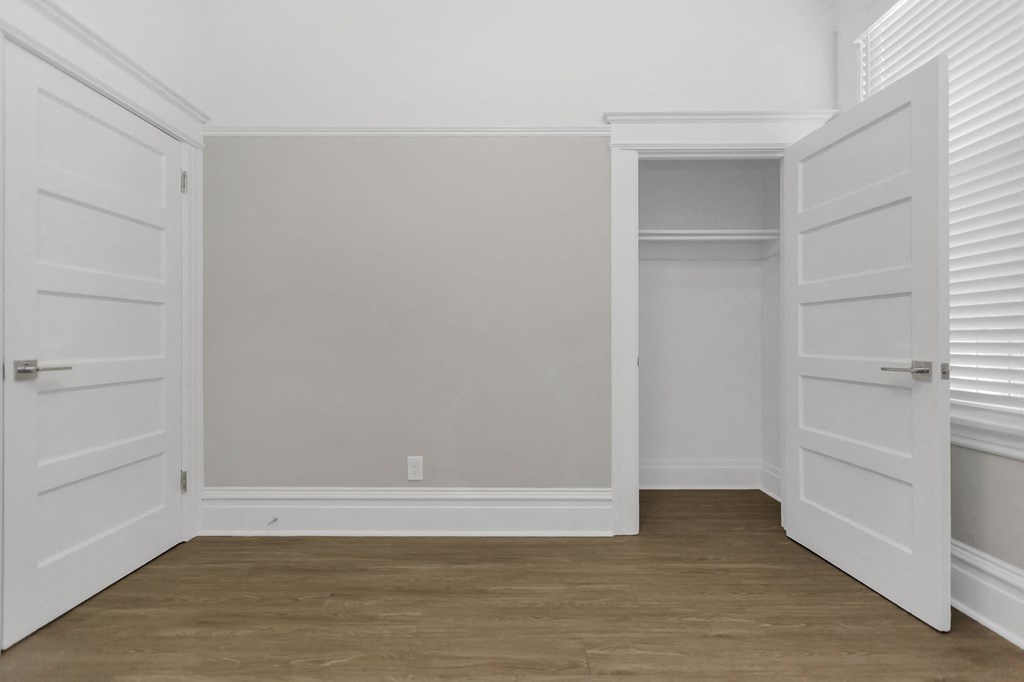 a bedroom with white walls and a closet with white doors