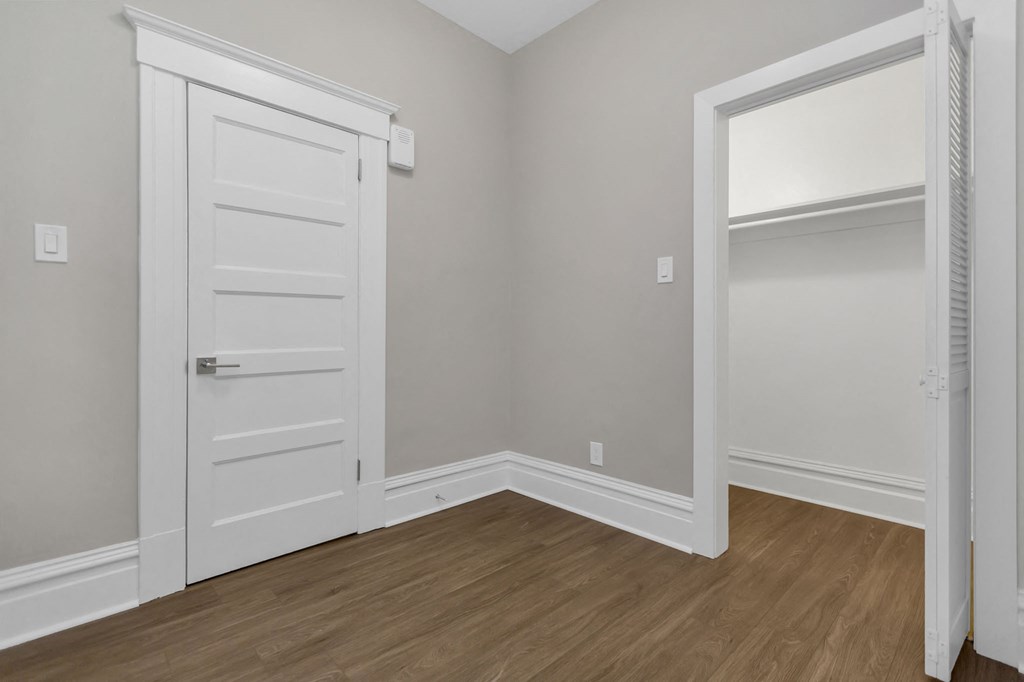 a bedroom with a door to a closet and a wooden floor