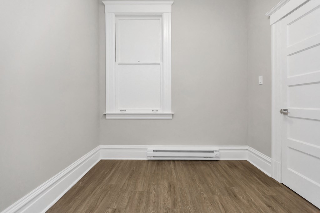 a room with white walls and a window and wooden floors