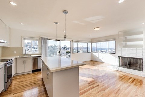 A modern kitchen with a large island and a view of the city.