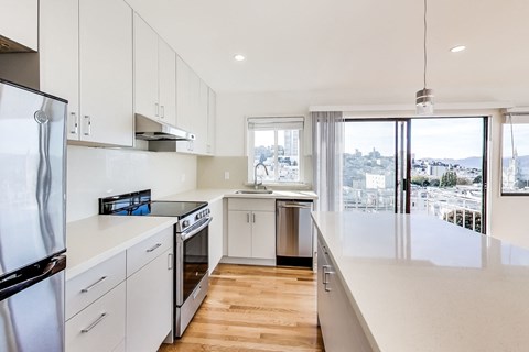 A modern kitchen with white cabinets and stainless steel appliances.