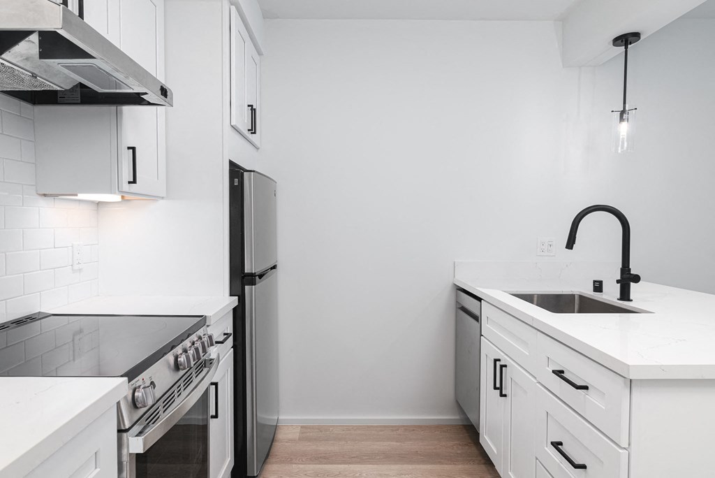 a kitchen with white cabinets and black appliances and a sink