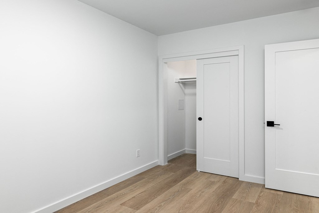 an empty room with white walls and a door to a closet