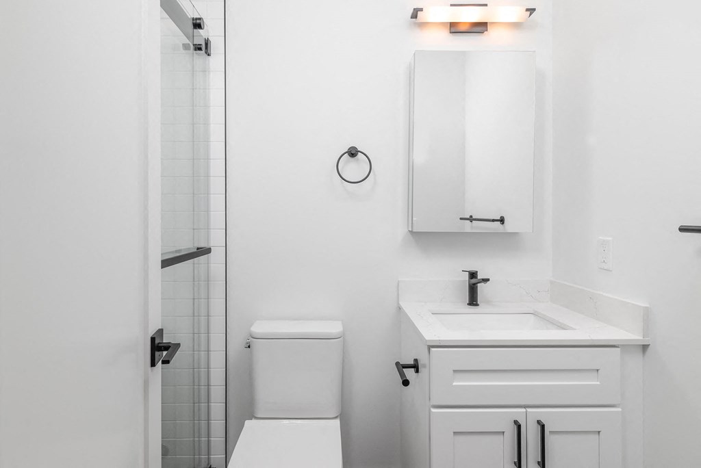 a white bathroom with a white sink and a white toilet