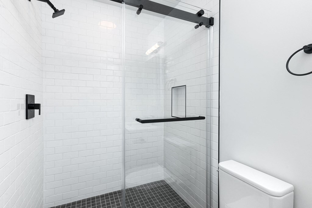 a white tiled bathroom with a glass shower door