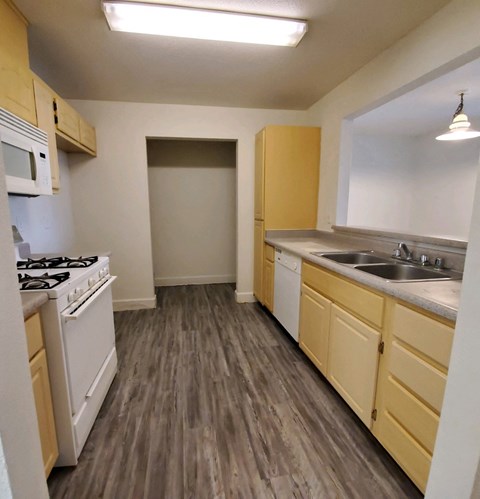 an empty kitchen with wood flooring and white appliances