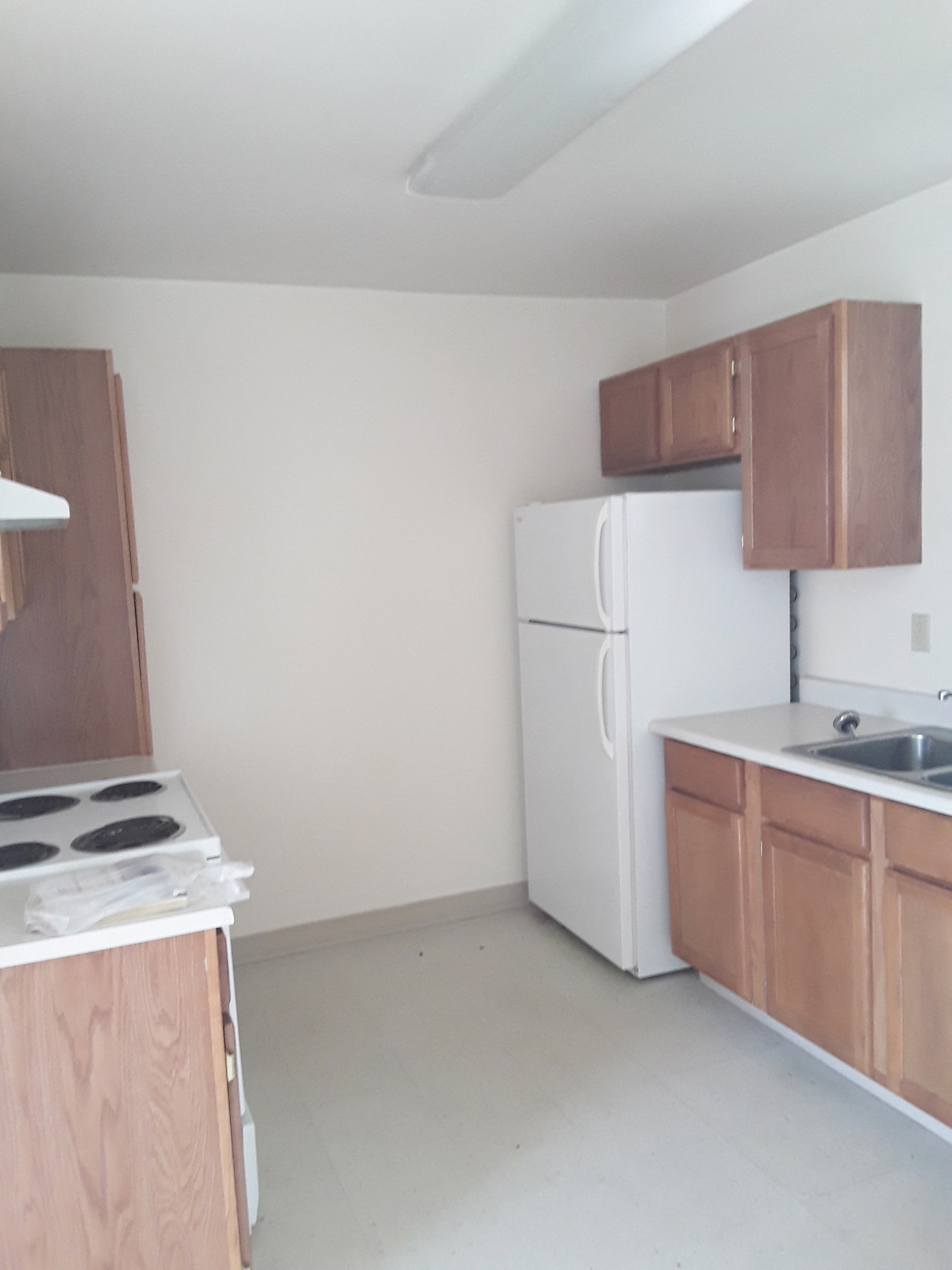 an empty kitchen with white appliances and wooden cabinets