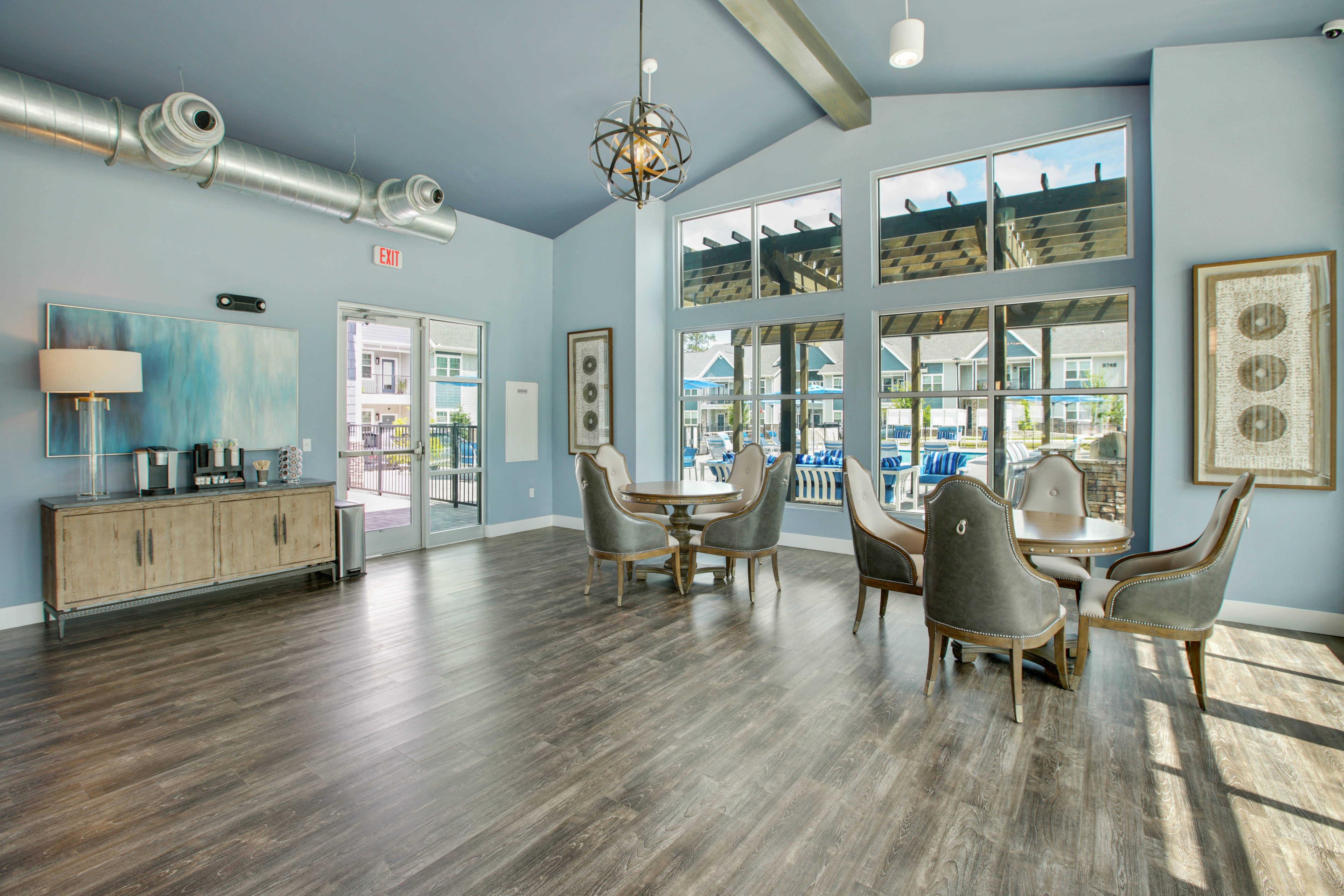 a living room with a table and chairs and large windows
