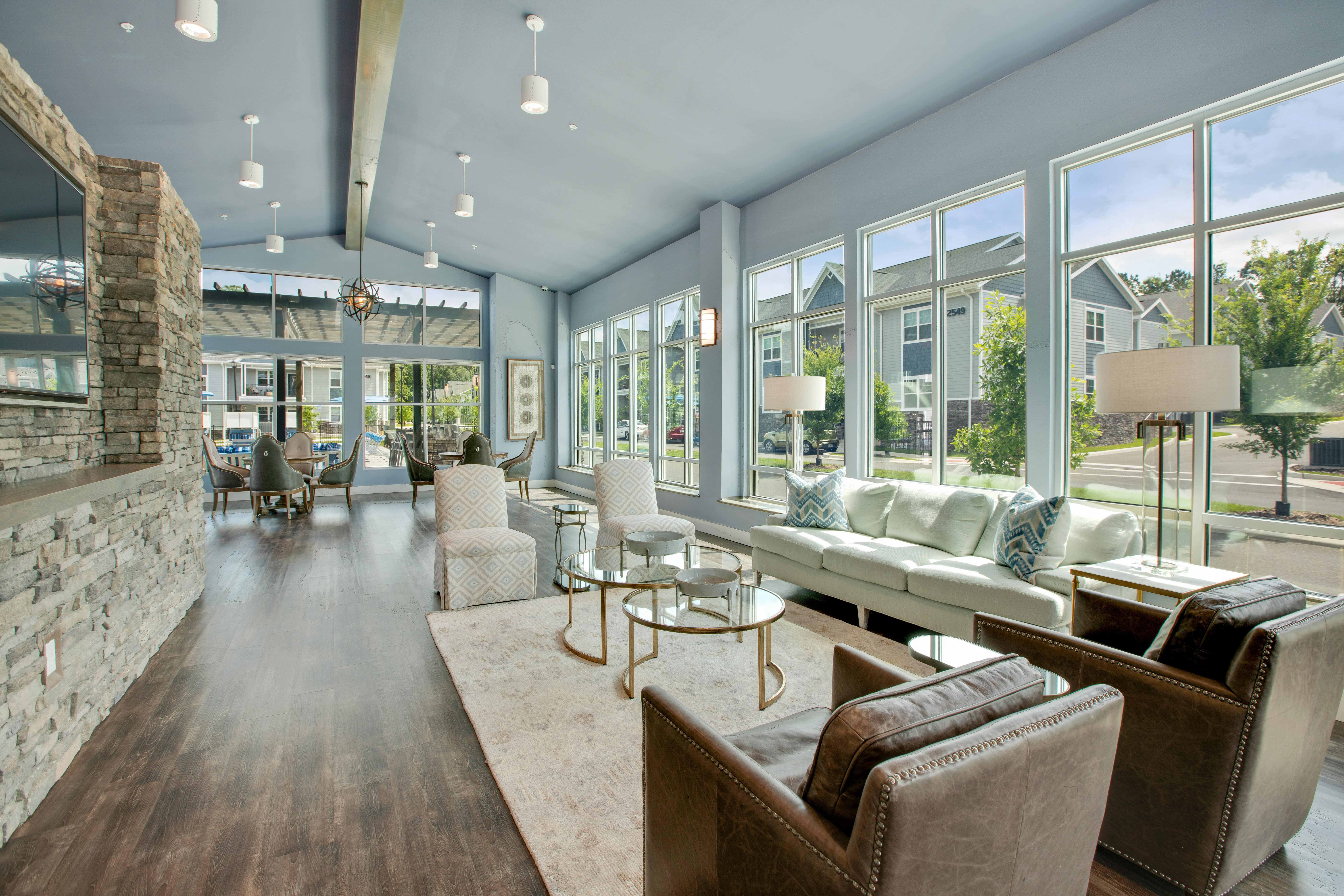 a living room with couches and chairs and large windows