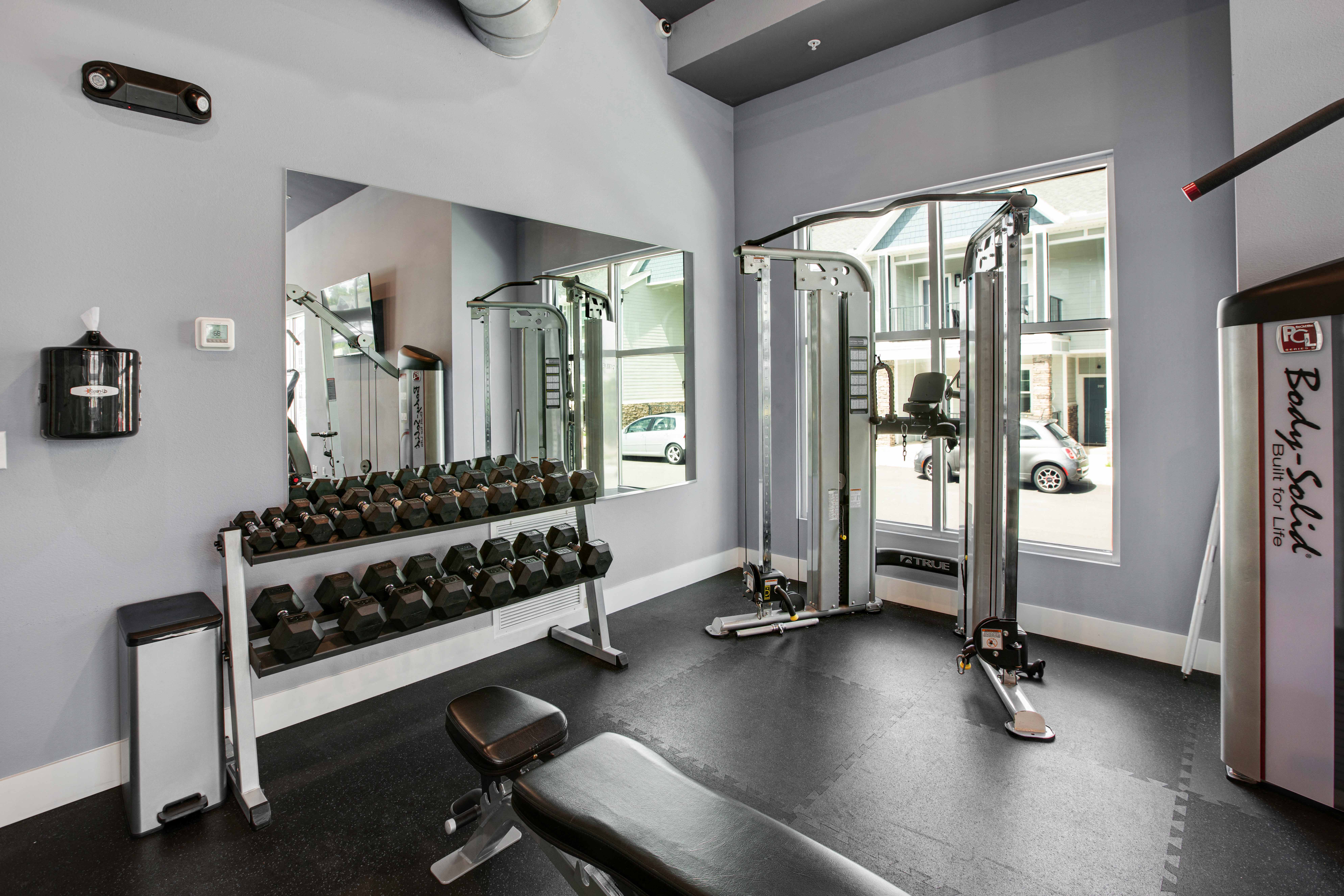 a gym with weights and mirrors and a window