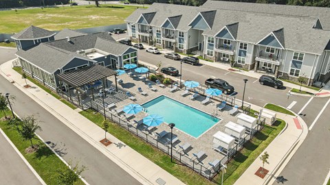 an aerial view of an apartment complex with a swimming pool and umbrellas