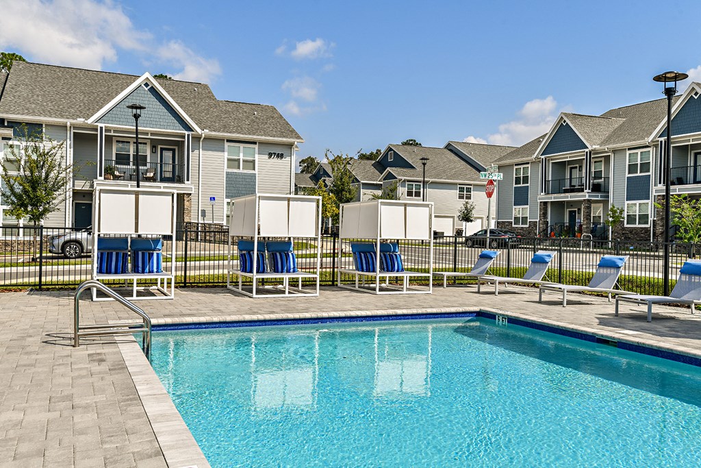 a swimming pool with blue chairs and houses in the background