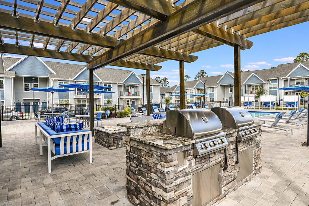 an outdoor patio with a grill and chairs and umbrellas