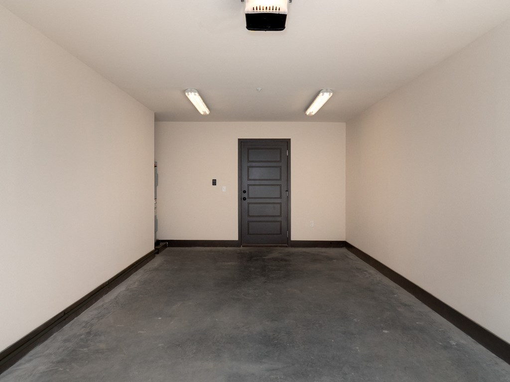 an empty room with a black door and a concrete floor