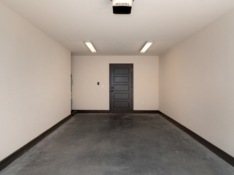 an empty room with a black door and a concrete floor