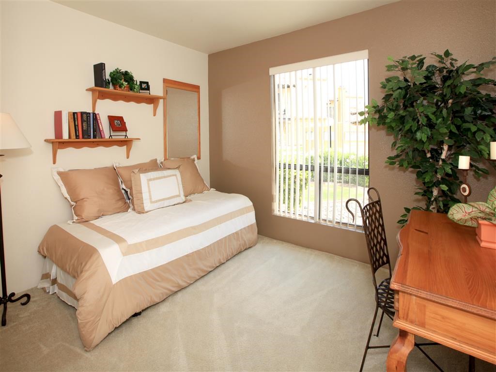 a bedroom with a bed and a desk and a window