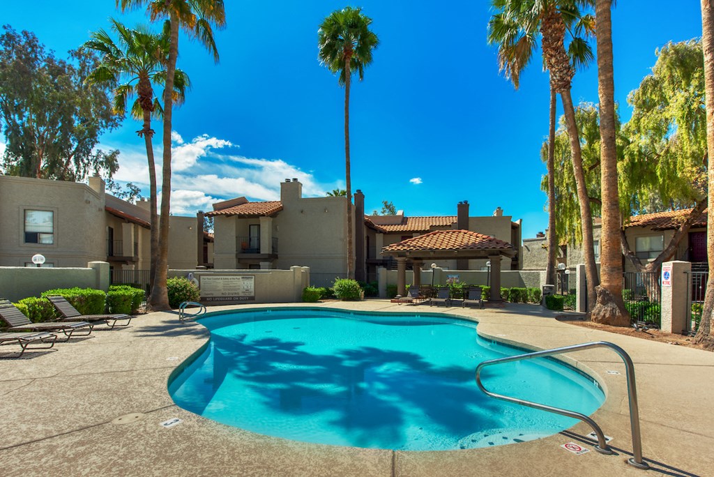 a swimming pool with palm trees and a building in the background