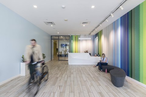 a man riding a bike through a lobby with a woman sitting on a couch