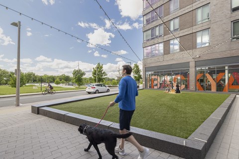a person walking a dog on a leash on a sidewalk next to a building